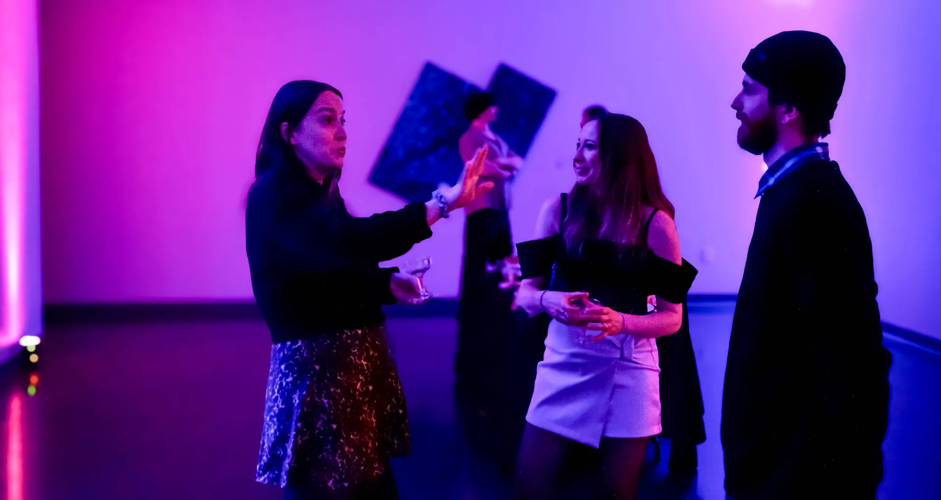 Guests mingling around the neon-lit bar with drinks in hand